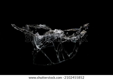 a crack on a broken glass mirror on a black background lines fragments bullet hole