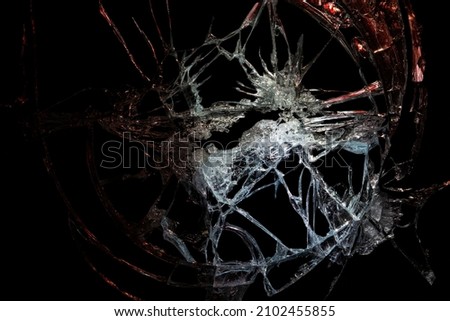 a crack on a broken glass mirror on a black background lines fragments bullet hole
