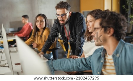 Lecturer Helps Scholar with Project, Advising on Their Work. Teacher Giving Lesson to Diverse Multiethnic Group of Female and Male Students in College Room, Teaching New Academic Skills on a Computer. Royalty-Free Stock Photo #2102457295