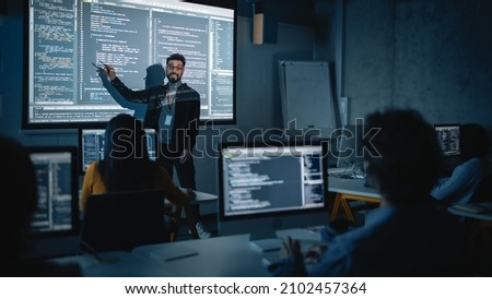 Teacher Giving Computer Science Lecture to Diverse Multiethnic Group of Female and Male Students in Dark College Room. Projecting Slideshow with Programming Code. Explaining Information Technology. Royalty-Free Stock Photo #2102457364