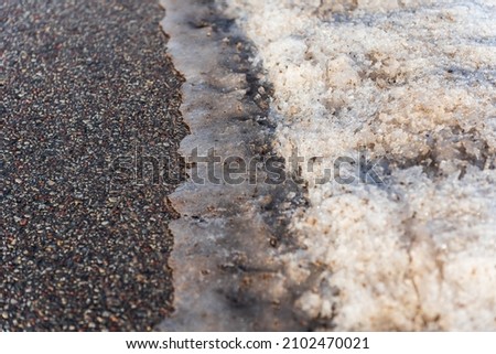 Melting snow on the asphalt road. Spring is approaching.