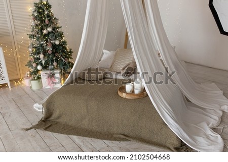 Bright large bedroom. New Year's interior, New Year's tree by the bed is decorated with balls. Christmas mood. bed with pillows
