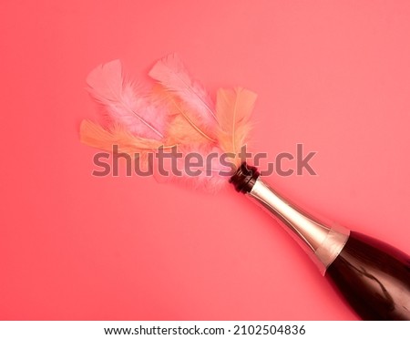 An open bottle of sparkling wine, peach and pink color feathers on a peach color background. Text space. Celebrations, Valentine's Day, weddings, anniversary. Minimal style. Top view. Flat lay.