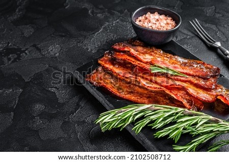 Fried crunchy Streaky Bacon stripes. Black background. Top view. Copy space Royalty-Free Stock Photo #2102508712