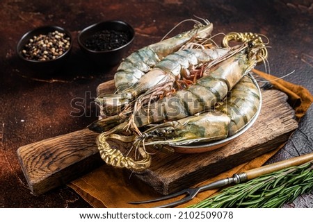 Whole Black tiger giant prawns shrimps in a skillet. Raw Seafood. Dark background. Top view