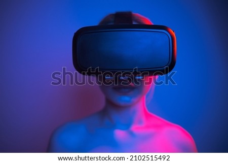woman in white shirt wearing vr glasses, futuristic studio photo with colorful lights on plain background