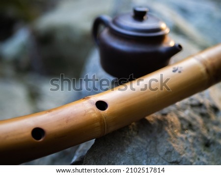 Bamboo flute with a master mark. We mean good luck. Against the background of a teapot made of clay.