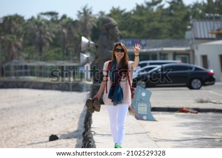 Photo of my wife waving from the parking lot of a beach on Jeju Island, South Korea.