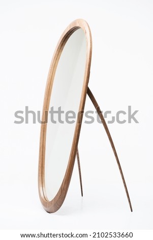 Stylish oval-shaped mirror made of wood on a white background