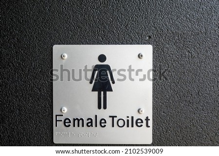 Female toilet signage with braille for the blind and a female shape icon on the wall