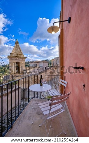 Italy, Sicily, Ragusa Ibla, view of an old house balcony and the baroque town in the background