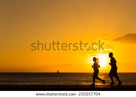Silhouette of people  jogging at the beach with sunset background