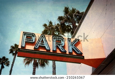 aged and worn vintage photo of neon park sign with palm trees