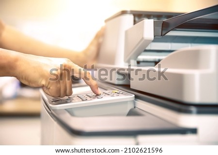 Copier printer, Close up hand office man press copy button on panel to using the copier or photocopier machine for scanning document printing a sheet paper and xerox photocopy. Royalty-Free Stock Photo #2102621596