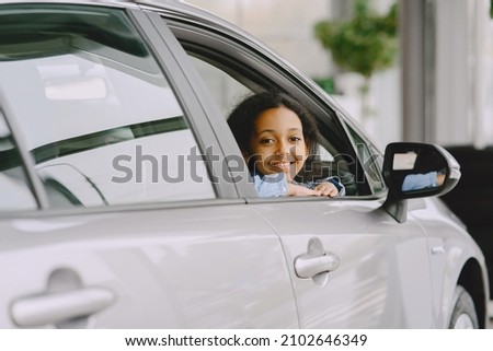 Cute african girl in modern car dealership Royalty-Free Stock Photo #2102646349