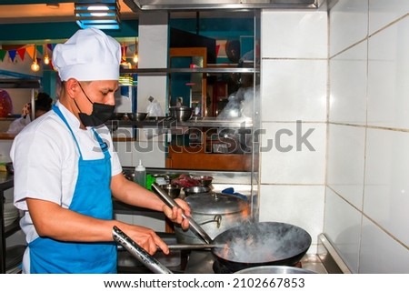 Modern kitchen. Chef moving ingredients in a wok preparing Peruvian meals. Kitchen photography