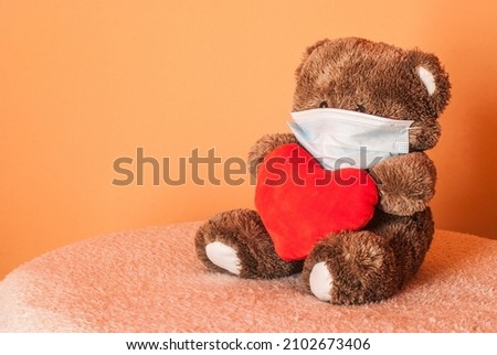 A plush teddy bear with red heart during pandemic. Quarantine Valentine's concept.  Royalty-Free Stock Photo #2102673406