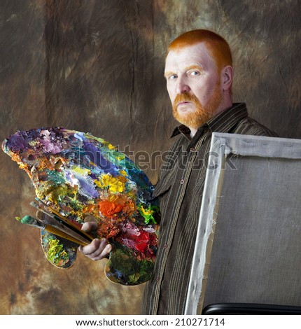 close-up portrait of an adult male artist with red hair and a beard at work studio on dark background