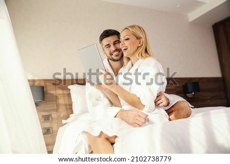 We celebrate love, a gentle lovely hug in the hotel's bed. Romantic moments to remember, a middle-aged happy loving couple in a hotel bathrobe taking a selfie photo.Love, lifestyle, emotions, feelings