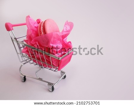 
Shopping trolley with macaroons and pink paper wrapping. Gift for March 8th. Valentine's Day. Women's Day. Womens shopping
