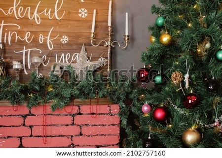 Multicolored illuminated christmas tree next to a flaming fireplace and gifts near the christmas tree