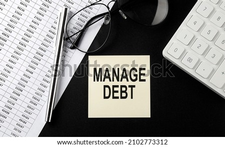Concept MANAGE DEBT message on sticker with glasses,chart and calculator on black background