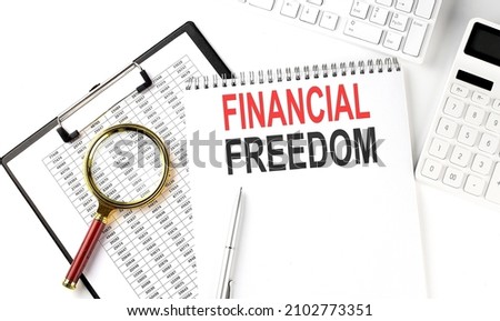 Office desk table with keyboard, notepad ,chart and calculator. Top view , text FINANCIAL FREEDOM
