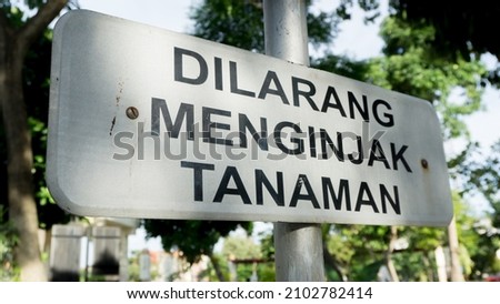 Do not step on flowers and plants sign wrote in Bahasa Indonesia "Dilarang Menginjak Tanaman"