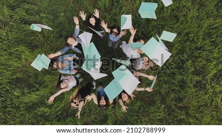 Students toss exercise books on their last day of school. Royalty-Free Stock Photo #2102788999