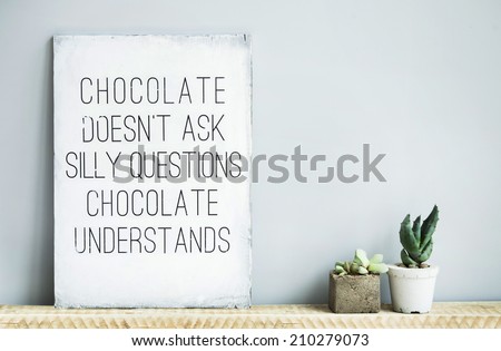 old wooden rustic poster with quote about chocolate with succulents in concrete pots. Scandinavian style home decoration. 