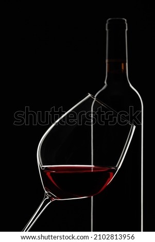 Glass and bottle of red wine on a black background. Selective focus.
