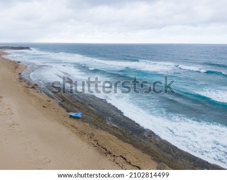 An aerial picture of a beach with waves in a cloudy day