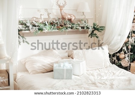 A part of beautiful christmas bedroom in light tone with christmas gifts and gold toys deer. New year interior. Selective focus.