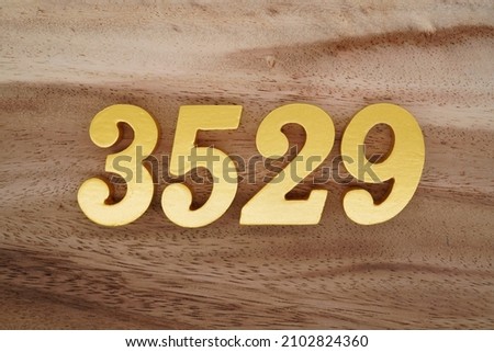 Golden Arabic numerals 3529 on a dark brown to white wood grain background.