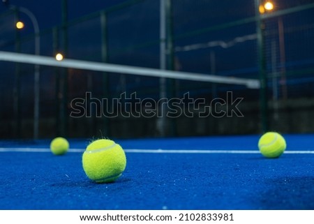 Selective focus. Three paddle tennis balls on the surface of a blue paddle tennis court. Sports concept. Royalty-Free Stock Photo #2102833981