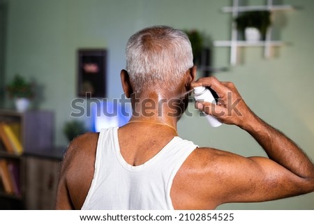 back view of old man using spray for neck pain relief at home - neck sprain,ache treatment and injuries due to aging Royalty-Free Stock Photo #2102854525