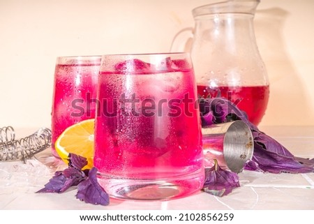 Purple basil organic drink, infused water cocktail with lemon and ice, on a tile background 