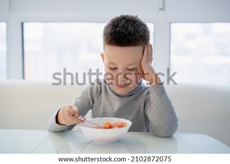 Little boy sits at the table and does not want to eat soup Royalty-Free Stock Photo #2102872075