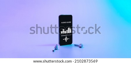 Audio excursion online app on digital mobile smartphone screen with music headphones on neon background. Listening audioguide. Education and leisure concept