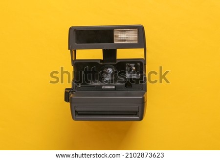 Retro 80s photo camera on yellow background. Top view. Flat lay