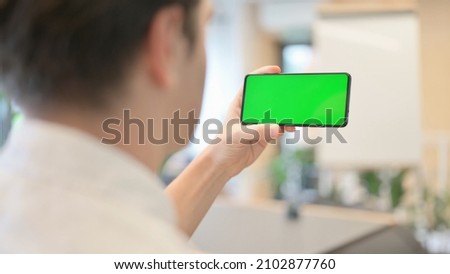 Young Man Looking at Smartphone with Green Chroma Screen