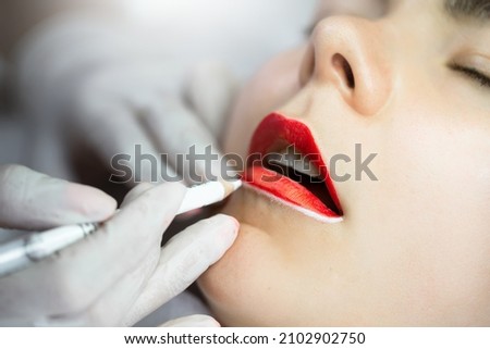 Professional permanent makeup artist and her client during lip blushing procedure Royalty-Free Stock Photo #2102902750