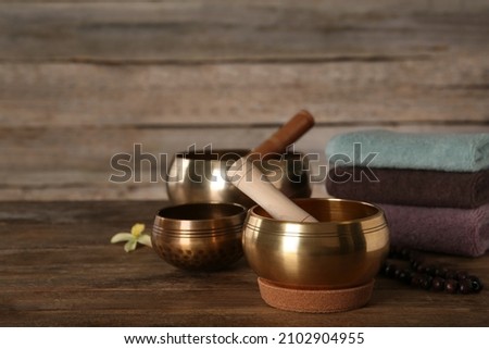Composition with golden singing bowls on wooden table, space for text