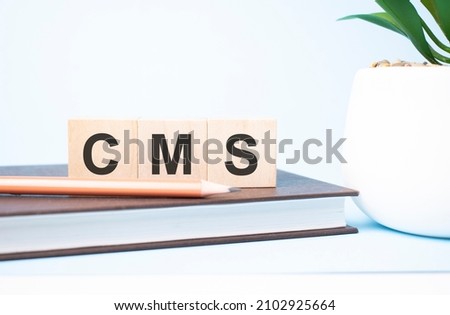 cms acronym on building blocks supported by two different size pencils. Copy space.