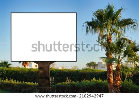 Blank horizontal billboard on the streets . Near palm trees and beautiful nature