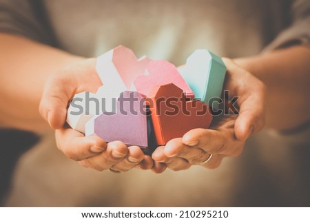 Bright paper hearts in woman hands. Toned picture