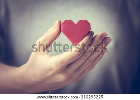 Red paper heart in woman hands. Toned picture