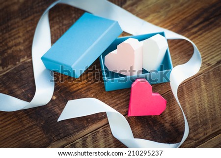 Bright paper hearts in gift box on wooden background. Toned picture