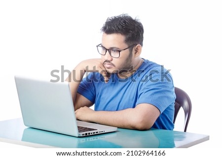 Studio shot of a handsome young boy using a laptop and looking stressed against a white background