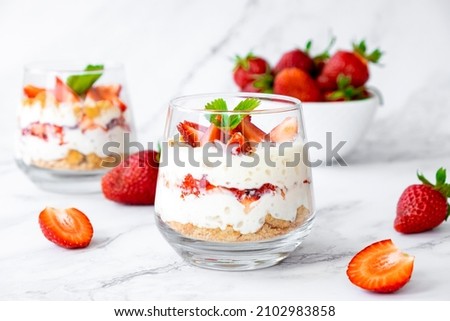 Italian strawberry tiramisu dessert with mascarpone and whipped cream, savoyardi crumb and fresh strawberry in glass on marble. Recipe of simple dessert, cheesecake, pudding or berry trifle cake. Royalty-Free Stock Photo #2102983858